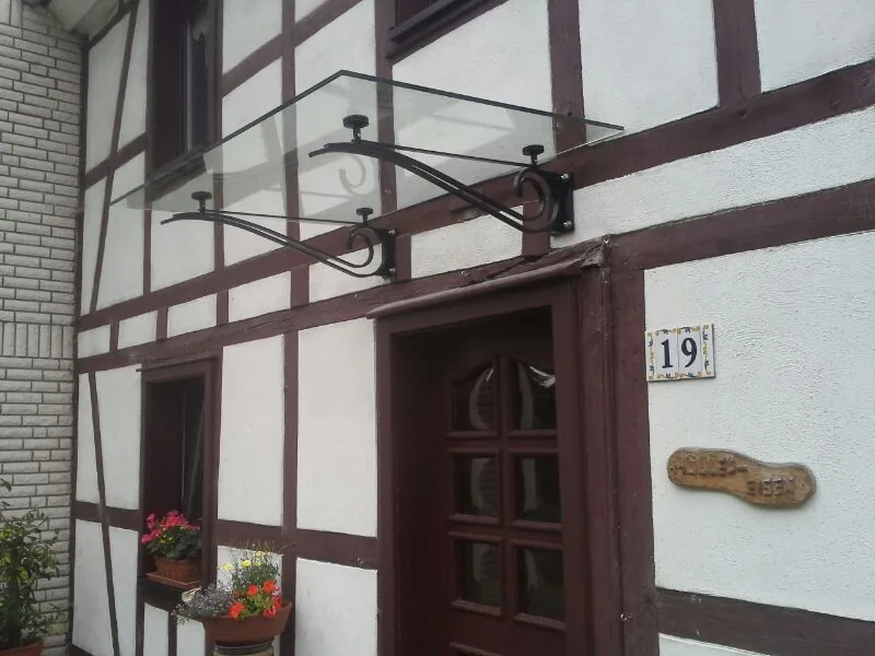 Glasvordach mit Schmiedeeisen-Konsolen über der Haustür eines Fachwerkhauses