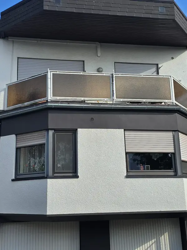 Balkongeländer mit alten braunen Glasscheiben vor dem Austausch